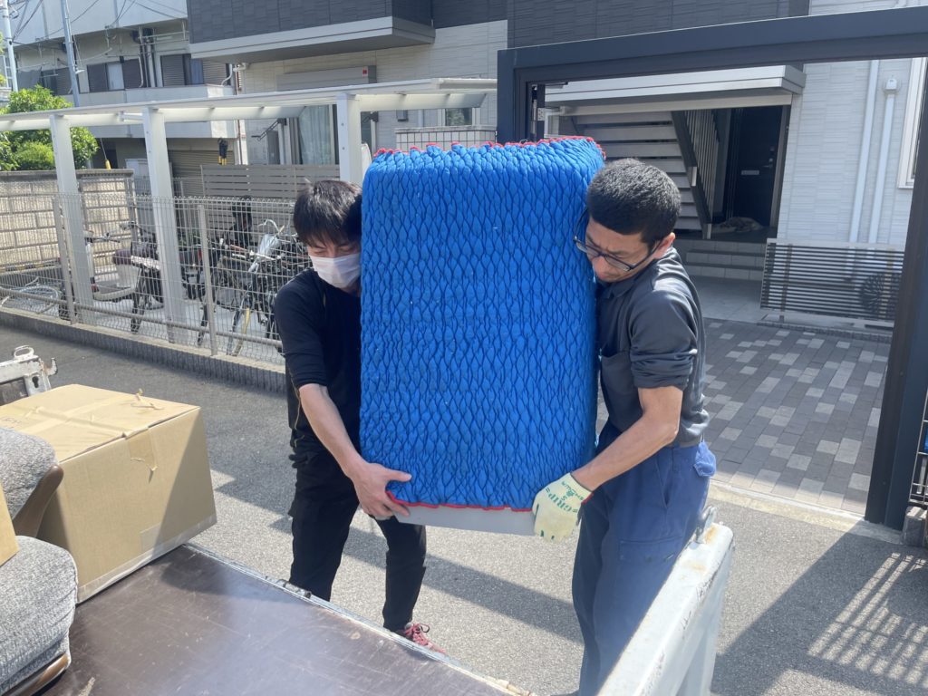 四條畷市で単身引越しと不用品回収を2名体制で行い、安全に大型家電を搬出する様子
